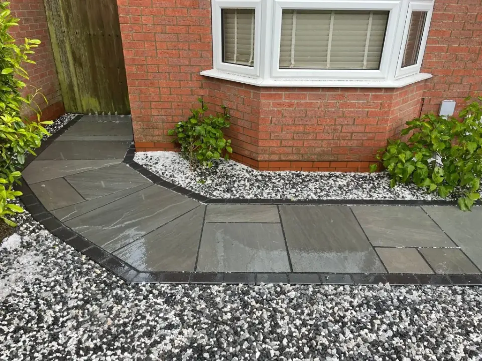 Grey slab path with white gravel border along a bay window wall